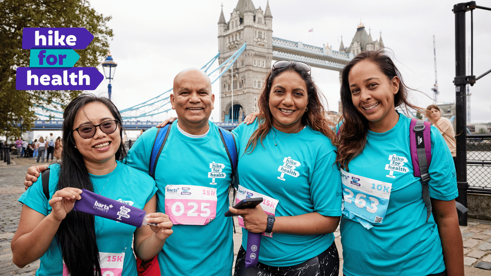 A group of people standing in front of London bridge dressed in Hike for Health T-shirts