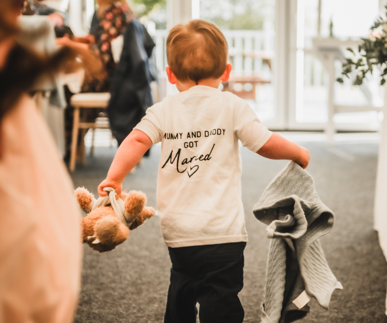 Alfie carrying a teddy bear and wearing a shirt saying Mummy and Daddy got married