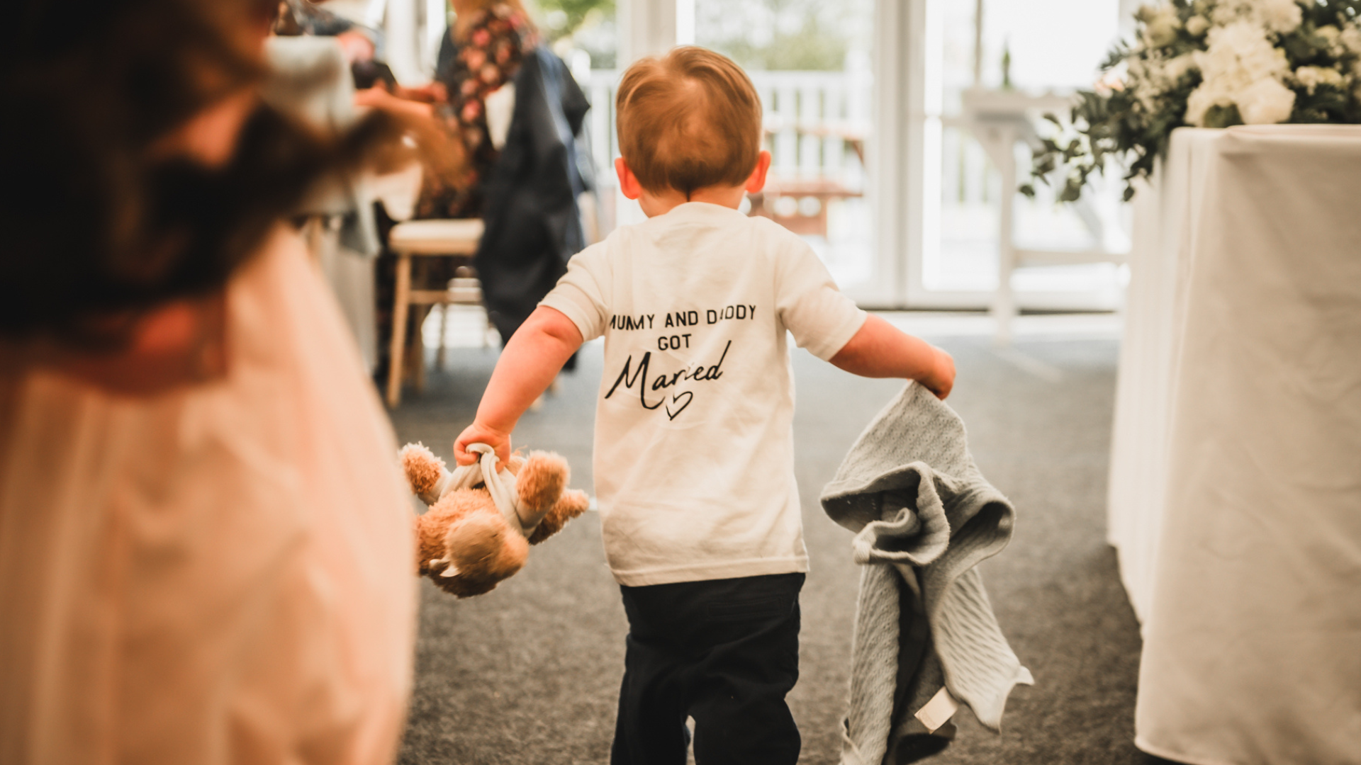 Alfie carrying a teddy bear and wearing a shirt saying Mummy and Daddy got married